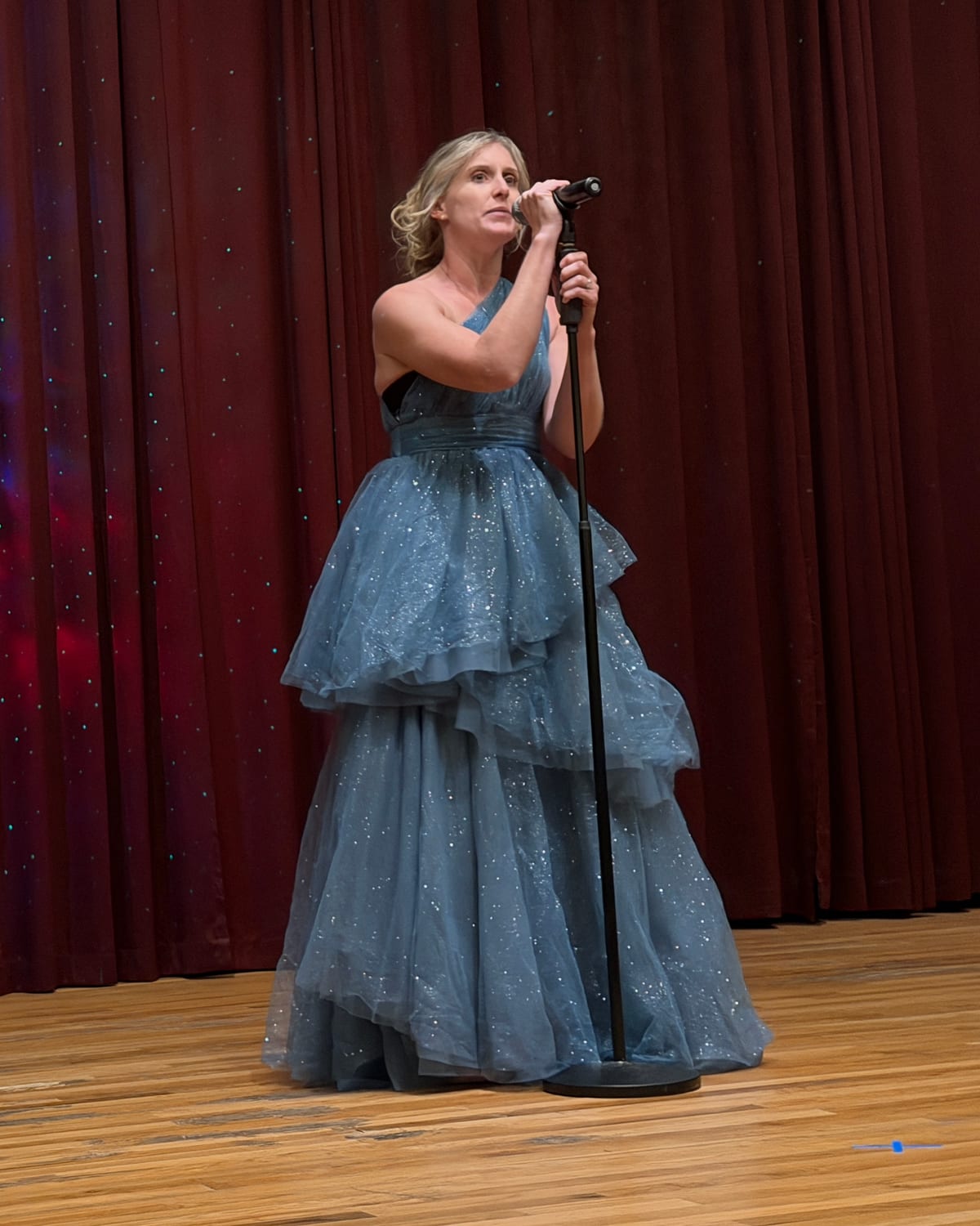 Reagan singing on stage in a blue gown
